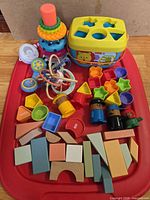 Overview of all toys including shape sorter, stacking rings, rattles, peg figures, wooden blocks