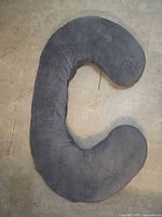 Gray C-shaped full-body pillow on floor full view