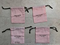 Front view of four pink kate spade dust bags showing logo and drawstrings