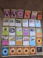 Full spread of roughly 36 Pokémon cards laid out in grid showing mix of Energy, Trainer and Pokémon cards