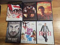 Front view of six DVD cases: Hockey Gold 2010, The Haunted Anthology, The Order, The Grey, Girls Just Want to Have Fun, Hitch