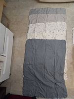 Full view of multiple-panel blue-gray, cream, and patterned baby quilt