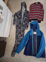 All three garments laid out: car-print onesie, striped sweater, blue jacket