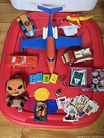 Overall view of lot on red tray showing vehicles, plush, stickers, books, cards and accessories