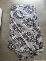 Folded gray and off-white damask duvet cover displayed on floor