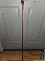 Full view of the wooden bamboo walking cane showing carved handle and rubber tip