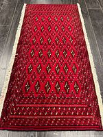 Full view of red Turkman wool rug with fringe and pattern