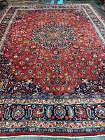 Full view of red field Mashhad rug showing medallion and borders