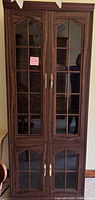 Full front view of tall curio cabinet showing four glass-pane doors and metal handles
