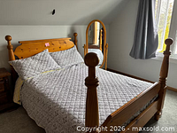 Full view of wooden double bed with mattress and cheval mirror beside it