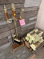 Full view of fireplace tool set on stand beside logs