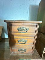 Front view of three-drawer wood unit showing all pulls