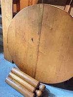 Round tabletop split for leaf with detached legs in foreground