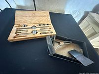 Open wooden case displaying dies, taps, wrenches; black box with files and other tools
