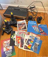 Overall lot showing Atari 2600 console, controllers, cords and manuals