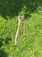 Long axe and shorter hatchet lying on grass showing handles and heads