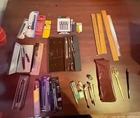 Overview of all pens, rulers, drafting set, refills and tools spread on tabletop