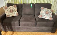 full view of brown faux suede couch with two decorative pillows