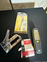 Staple gun, packaged engraver, LED work light, two boxes staples displayed on table