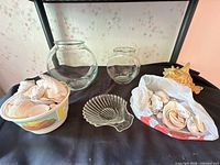 Two clear glass fish bowls, shell dish, tubs of sea shells displayed