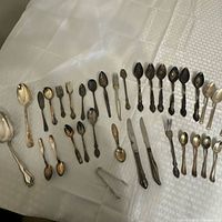 Overview of assorted silver-plated flatware laid out on table
