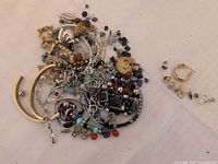 Pile of mixed broken jewellery and separate group of single earrings