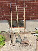 Three rakes leaning against wall showing full length and type