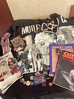 Overview of entire lot showing wall flag, guitar strap, pins, magazines, books