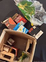 Overview of open cardboard box containing various nail boxes and plastic bag of nails
