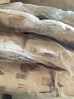 Stack of four beige outdoor cushions in plastic with brown fern pattern