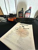 Chainsaw with manual and two oil bottles on table