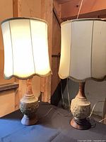 Both 1970s ceramic table lamps showing bases, shades, cords, one illuminated