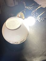 white glass globe on table with lit bulb, chain and cord visible