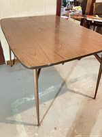 Full view of the rectangular retro kitchen table showing top surface, edge trim, and metal legs