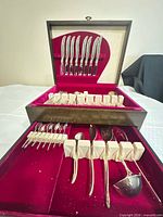 Overall view of flatware arranged in open chest, showing knives, forks, spoons, serving pieces and chest interior