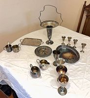 All 18 silver-plated pieces arranged on table: epergne, trays, goblets, mugs, candy dish, creamer, sugar, spoon, fork