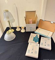 Group shot of boxes of candles, brass lamp with shade, extra glass shade, ceramic holders