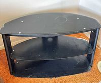 Front view of black three-shelf TV stand showing curved shape and shelf configuration
