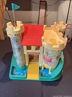 Front view of Fisher-Price Play Family Castle showing drawbridge down, towers, flag, moat base