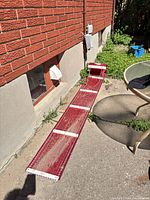 Full view of red toboggan sled leaning against wall