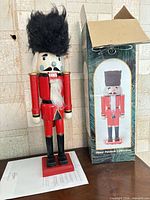 Full view of wooden nutcracker beside box