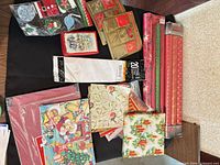 Group of Christmas wrapping rolls, folded sheets, gift tag packs, gift boxes