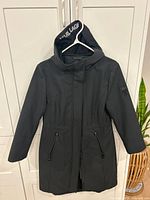 Front view of black Karl Lagerfeld hooded rain jacket hanging
