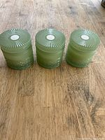 Top view of three matching green glass candle jars with lids
