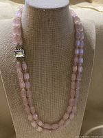 Full view of double-strand pink bead necklace on display bust