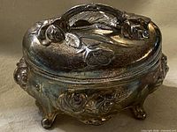 Closed jewelry box front three-quarter view showing floral relief and tarnish
