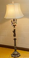 Full view of ornate brass cherub floor lamp with shade