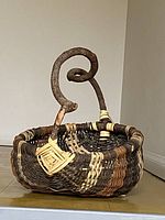 Full view of woven buttocks basket with curled branch handle