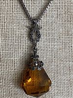 Full view of necklace showing chain, filigree links and amber glass pendant