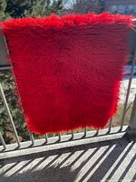 Full view of the red wool shag rug hanging over railing
